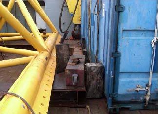 Injured person's ankle was trapped between yellow spreader bars and blue freight container